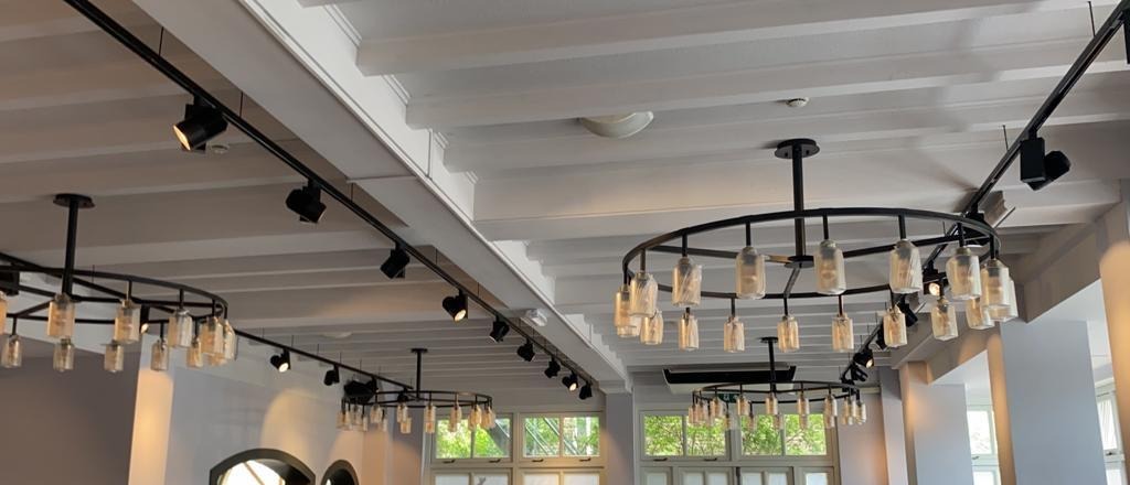 Wit plafond met spots op zwarte rails en twee ringvormige hanglampen